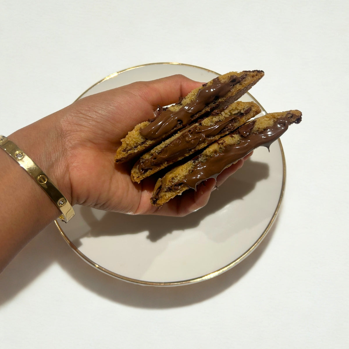 Close-up of gooey Nutella-filled cookie held in hand – freshly baked stuffed chocolate cookie by Queen Cookies for premium snacking in India