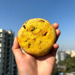 Hand holding Kesar Pista Cookie with saffron and pistachios, premium eggless dry fruit cookie to Shop online from Queen Cookies