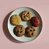 Assorted handcrafted eggless cookies by Queen Cookies India, featuring red velvet, chocolate chunk, dry fruit, saffron pistachio, and choco chip varieties — perfect for premium gifting and nationwide delivery from queencookies.in