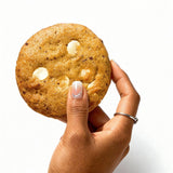 Hand holding a Biscoff White Choco Chip Cookie from Queen Cookies – soft, golden, and filled with creamy white chocolate chips