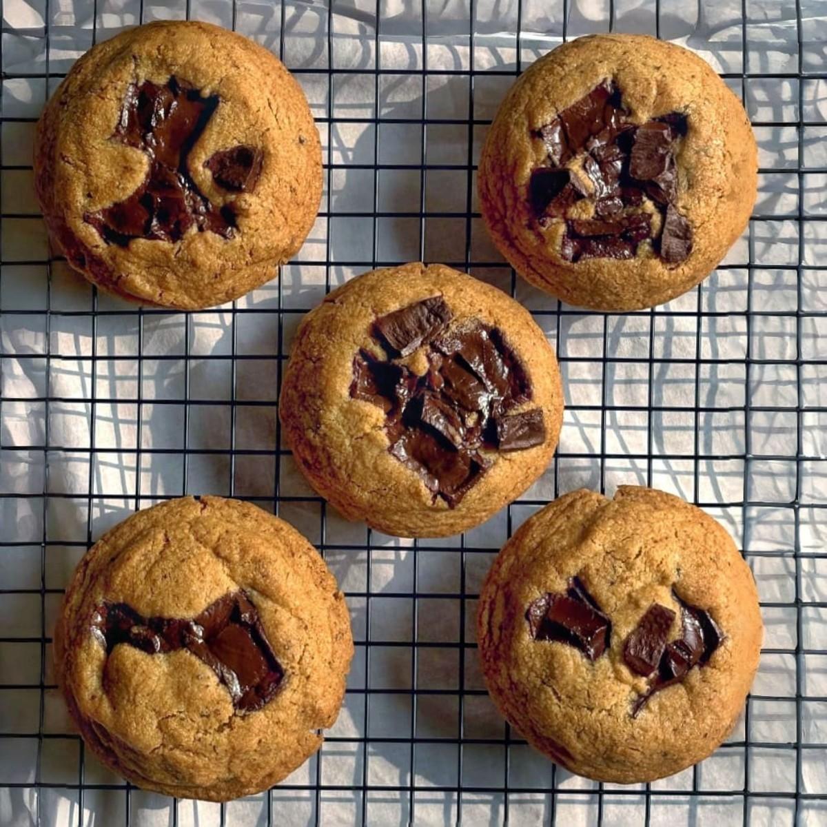 Five chocolate chip cookies are on a cooling rack against a light background. Shop online in India