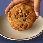 Hand holding eggless dry fruit cookie with nuts and berries, order fresh online from Queen Cookies India