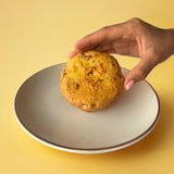Hand holding Kesar Pista Cookie with saffron and pistachios, premium eggless dry fruit cookie to buy online in India from Queen Cookies