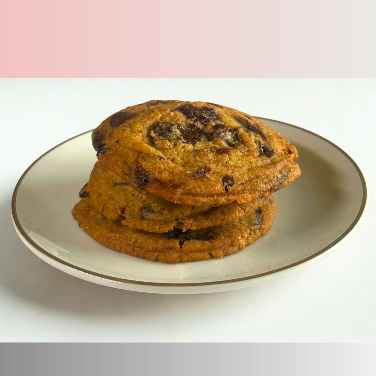 Three handcrafted choco chunk cookies stacked on a white plate, freshly baked by Queen Cookies India.
