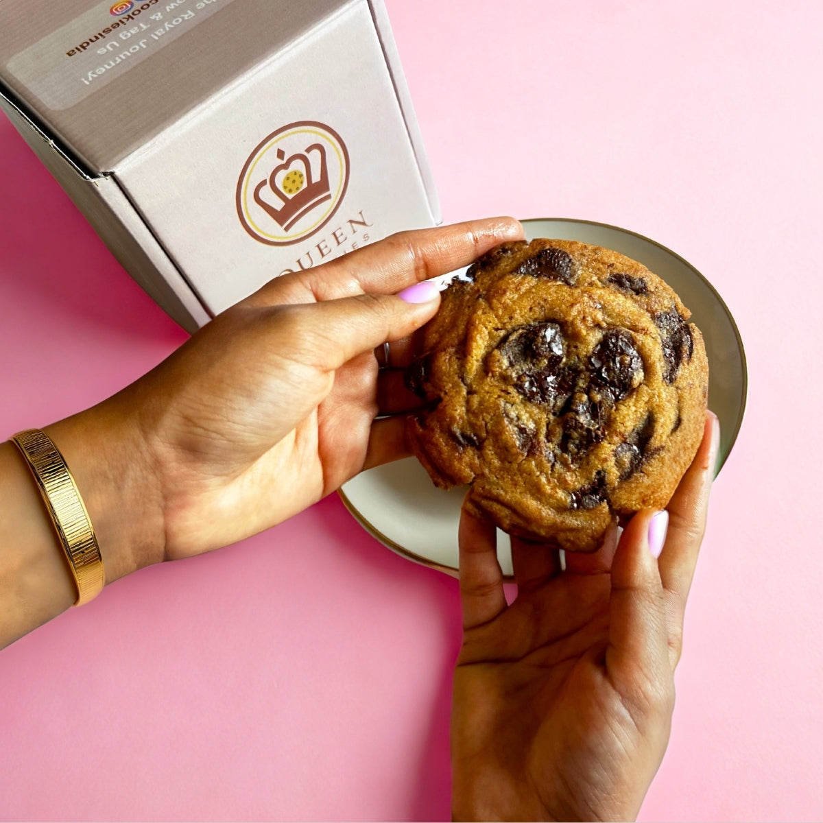 Hand holding a chunky chocolate cookie by Queen Cookies India – freshly baked, indulgent, and perfect for gifting or snacking.