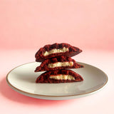 Cross-section of stacked red velvet cookies filled with cream cheese, highlighting the gooey center from Queen Cookies