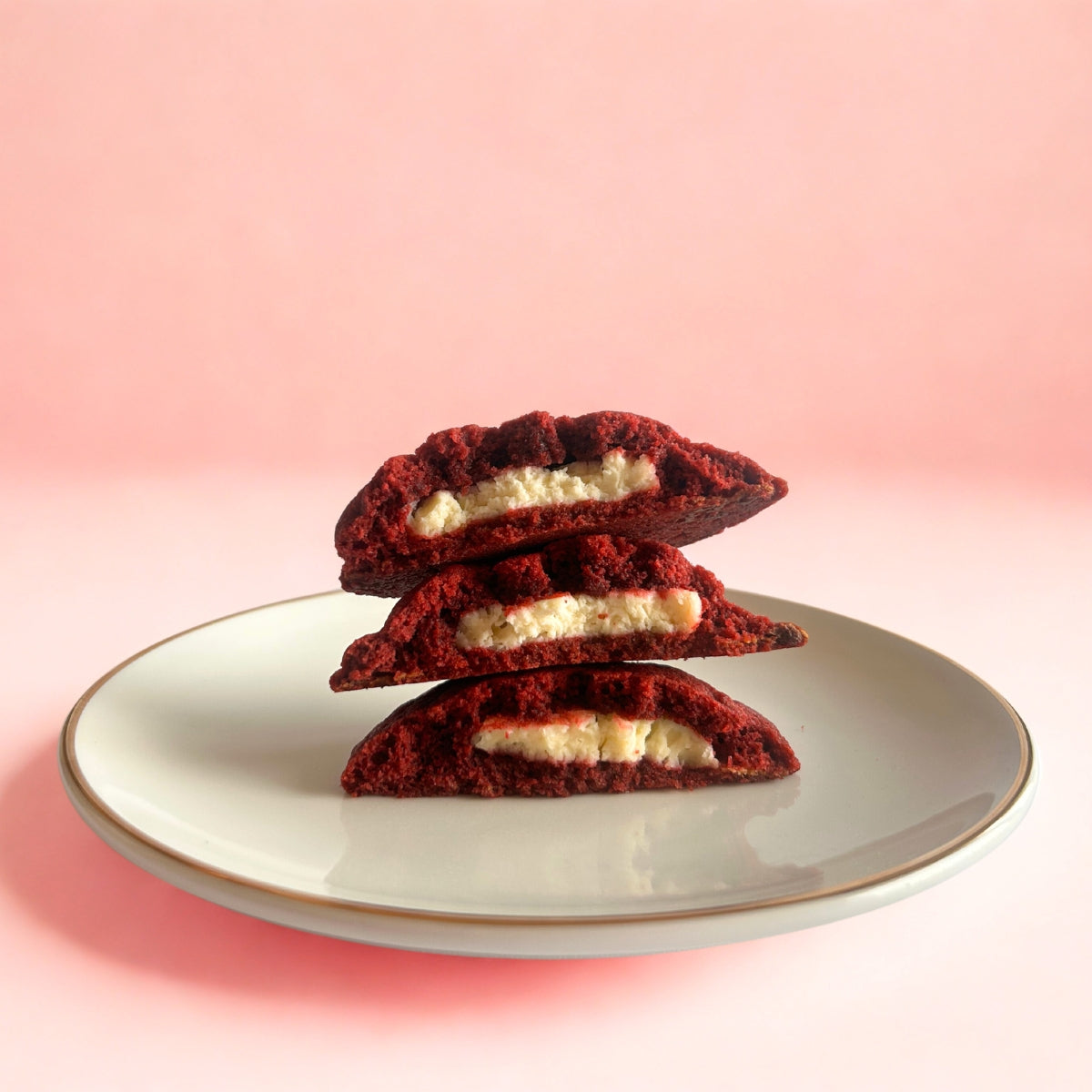 Cross-section of stacked red velvet cookies filled with cream cheese, highlighting the gooey center from Queen Cookies