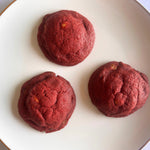 Top view of three red velvet cream cheese cookies on a white plate, fresh-baked and eggless by Queen Cookies